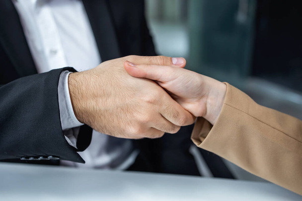 hombre y mujer en el desgaste formal estrechan las manos en la oficina teniendo acuerdo exitoso sobre el nuevo proyecto de negocio. - Foto, imagen