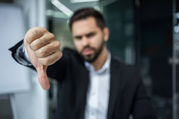 бизнесмен Показать знак провала. Бизнесмен с проблемами в бизнесе показывает большой палец в офисе. - Фото, изображение