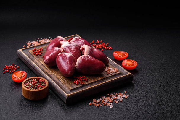Raw turkey or chicken hearts with salt and spices on a dark concrete background - Photo, Image