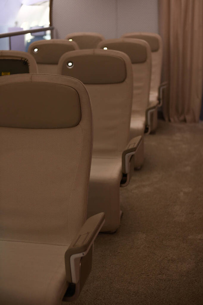 現代的なハッチクラスの座席を備えたプロトタイプの航空機. 照明が付いているベージュの座席そして港. 座席が2つある列. パイプライン. - 写真・画像