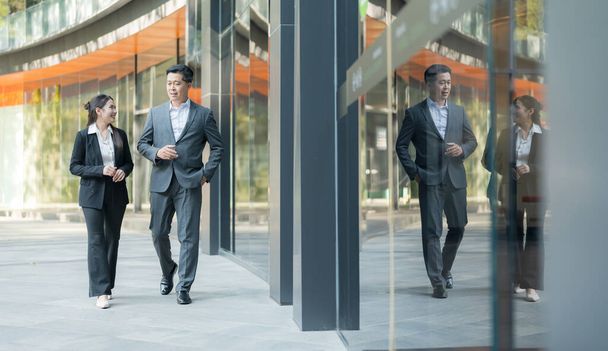 Два професіонали, що йдуть пліч-о-пліч, ведуть розмову за межами корпоративної будівлі - Фото, зображення