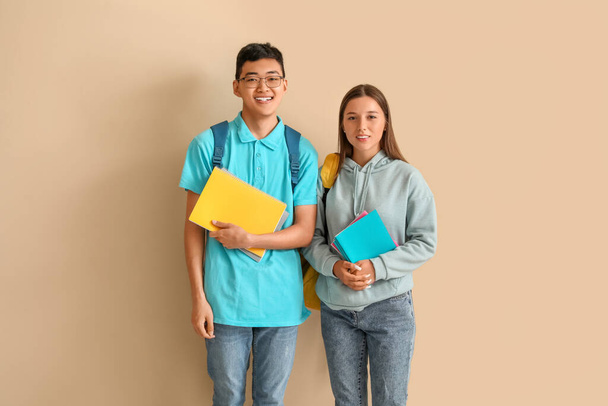 Happy students with backpacks and notebooks on beige background - Photo, Image