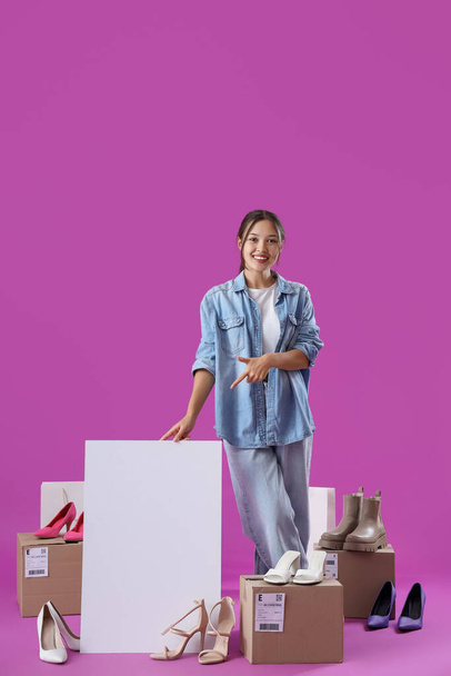 Mladý asijský prodejce s prázdným plakátem a boty na fialovém pozadí - Fotografie, Obrázek