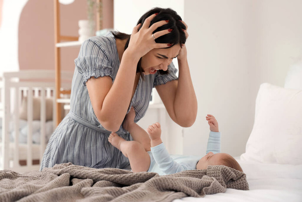 Dühös fiatal nő a baba szenved posztnatális depresszió a hálószobában - Fotó, kép