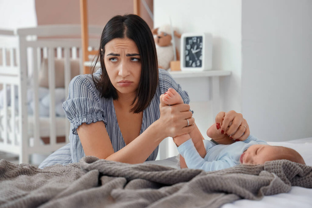 Junge Frau mit Baby leidet an postnataler Depression im Schlafzimmer - Foto, Bild