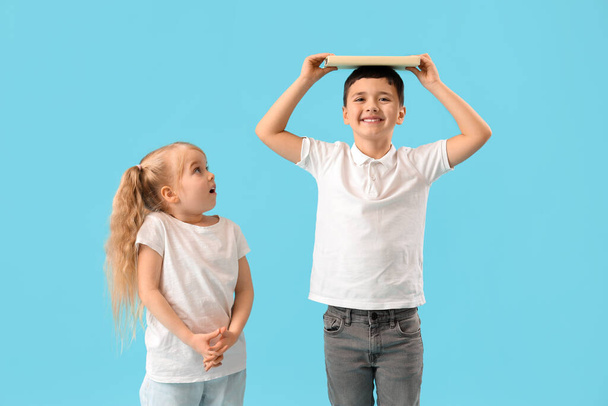 Niedliche kleine Kinder messen Höhe auf blauem Hintergrund - Foto, Bild