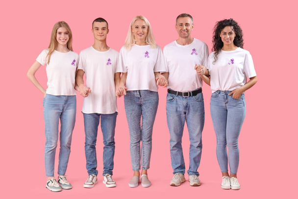 Menschen mit Lavendelbändern halten Händchen auf rosa Hintergrund. Weltkrebstag - Foto, Bild