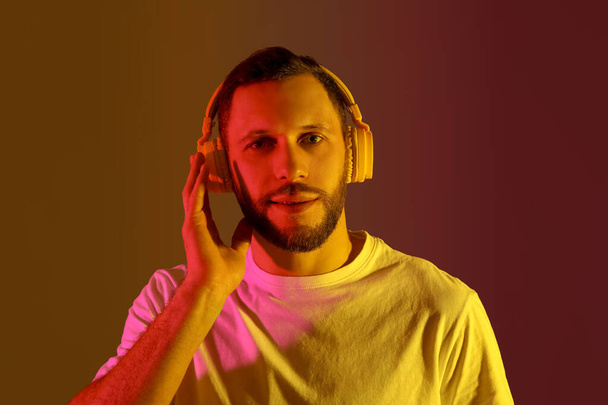 Young man in modern headphones on colorful background - Photo, Image