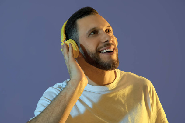 Young man in modern headphones on blue background - Photo, Image
