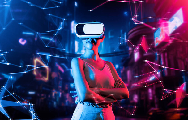 Vrouwelijke staan in virtual reality cyberpunk stijl gebouw slijtage VR headset aansluiten metaverse, toekomstige cyberspace community technologie, Ze zet lichaam naar links gekruiste arm en zelfverzekerde pose. Hallucinatie. - Foto, afbeelding
