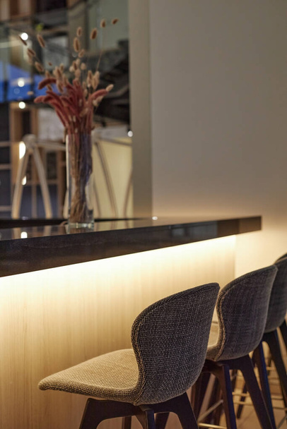 Imagen de fondo vertical del mostrador de bar en el interior de la cafetería moderna con sillas altas y acentos de iluminación led - Foto, imagen