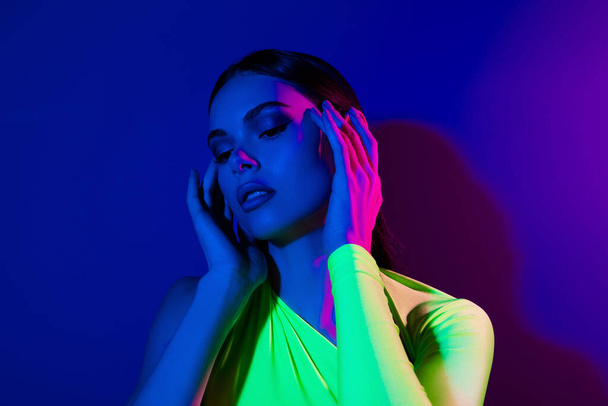 Portrait of fancy pretty charming model girl fingers touch face isolated on multicolor neon lights background. - Photo, Image