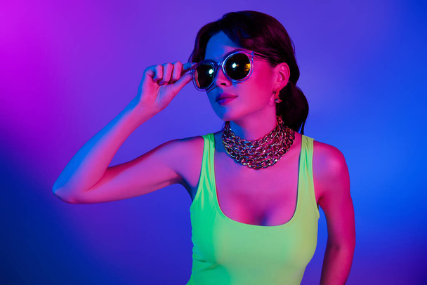Photo of girl in retro style look aside touch sunglass isolated violet neon color background. - Fotoğraf, Görsel