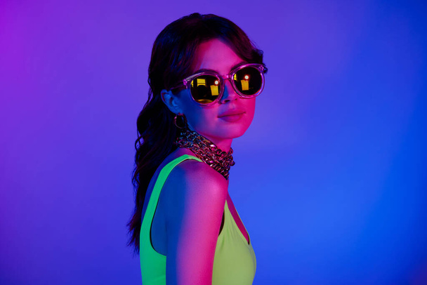 Kuva viileä tyttö käyttää aurinkolasi kehonpuku katso kameran eristetty elinvoimainen neon tausta. - Valokuva, kuva