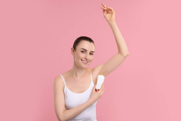 Beautiful woman applying deodorant on pink background - Fotografie, Obrázek