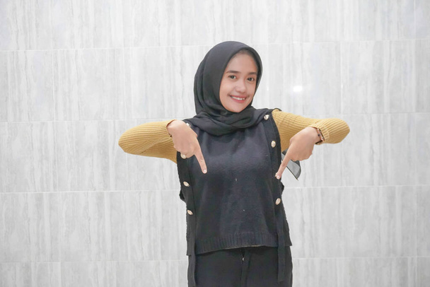 Egy sárga ujjú fekete hidzsábot viselő ázsiai indonéz nő kifejezése - Fotó, kép