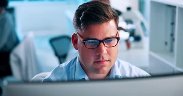 Science, research and man at computer thinking, reading and checking results in pharmaceutical study. Glasses, reflection and person on website for medical review, report or typing lab ideas at desk. - Footage, Video