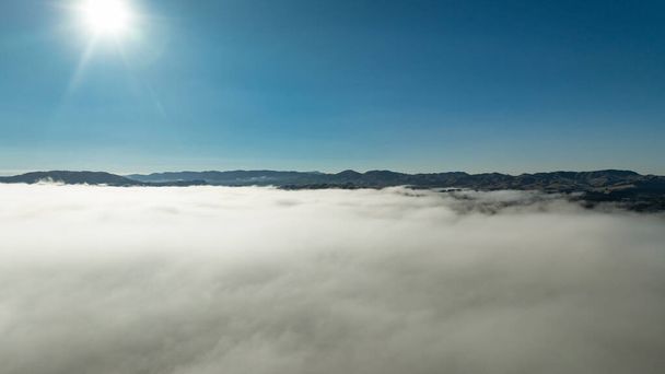 Scène aérienne de nuages bas dans la vallée avec la chaîne de montagnes au-dessus des nuages - Photo, image