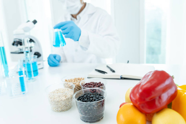 Tutkija tarkistaa kemialliset elintarvikejäämät laboratoriossa. Tarkastusasiantuntijat tarkastavat hedelmien, vihannesten laadun. lab, vaarat, ROHs, löytää kiellettyjä aineita, saastuttaa, Mikroskooppi, Mikrobiologi - Valokuva, kuva