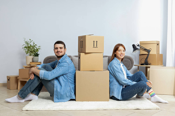 Концепция переезда, пара мужчина и женщина с коробками в квартире. - Фото, изображение