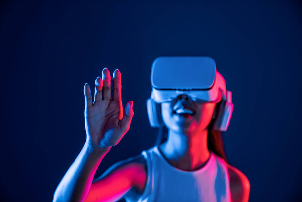 Slimme vrouw in cyberpunk neon licht dragen VR-headset aansluiten metaverse, futuristische cyberspace community technologie. Elegante vrouw gebruikt hand aanraken gegenereerd virtueel object. Hallucinatie. - Foto, afbeelding
