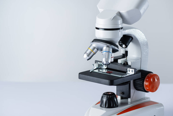 Mikroskop auf weißem Hintergrund mit Kopierraum. Blutprobe auf einem Glas unter dem Mikroskop. HIV-Testforschung. - Foto, Bild