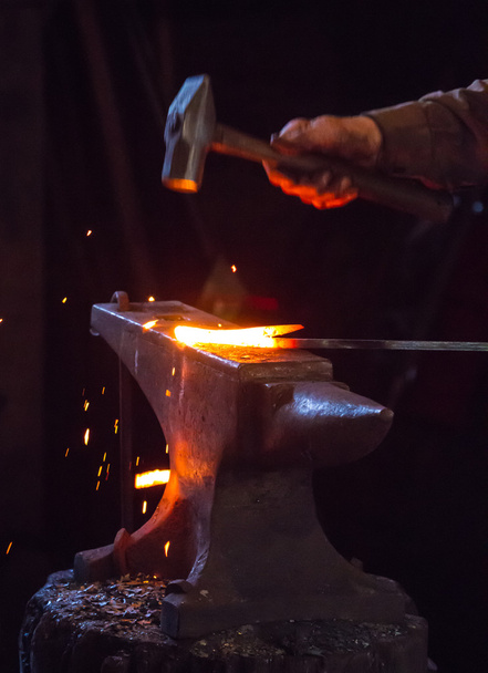 Σιδεράς σφυρηλάτηση μια ράβδο θερμό μέταλλο - Φωτογραφία, εικόνα