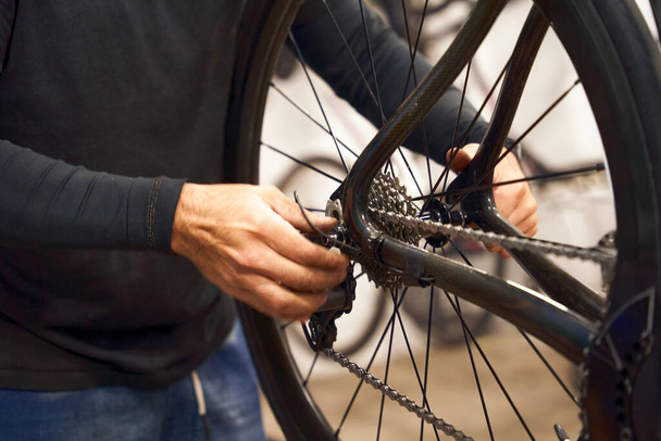 Bisiklet atölyesinde çalışan erkek tamirciye yakın çekim. Bisiklet servisi, tamir ve geliştirme - Fotoğraf, Görsel