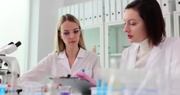 Duas cientistas discutem os resultados da pesquisa em um laboratório. Trabalhando em conjunto em pesquisa médica - Filmagem, Vídeo