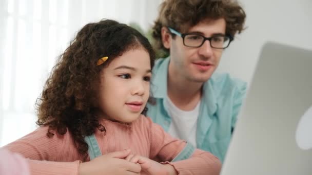 American girl putting pencil in the ear while looking at laptop screen. Happy caucasian father pointing at computer and explain coding engineering prompt and AI generate to lovely daughter. Pedagogy. - Footage, Video