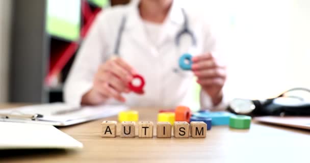 Doctor holds in hands multicolored cubes and text autism. Development of children with autism and causes symptoms diagnosis and treatment - Footage, Video