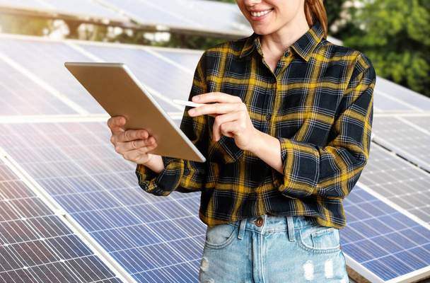 Ingeniera femenina comprueba el estado técnico de los paneles solares utilizando una tableta digital. - Foto, imagen