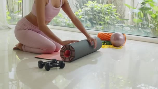 Обрізаний знімок невпізнаваної спортсменки в активному одязі викидає йога килимок під час підготовки до тренувань - Кадри, відео