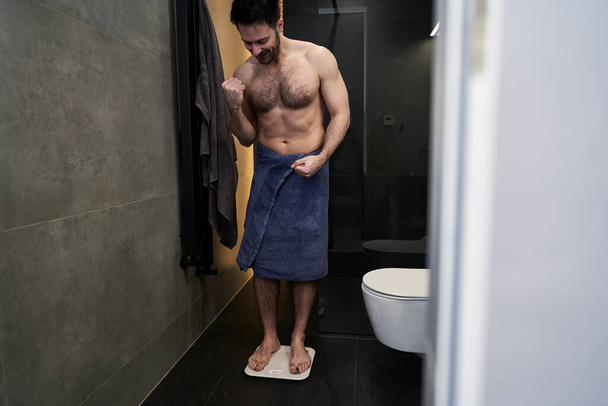 Satisfied man using bathroom scale  - Foto, imagen