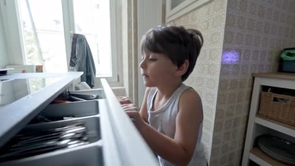 Uno mismo-Suficiente Little Boy Fetches cuchara del cajón de la cocina para su comida - Imágenes, Vídeo