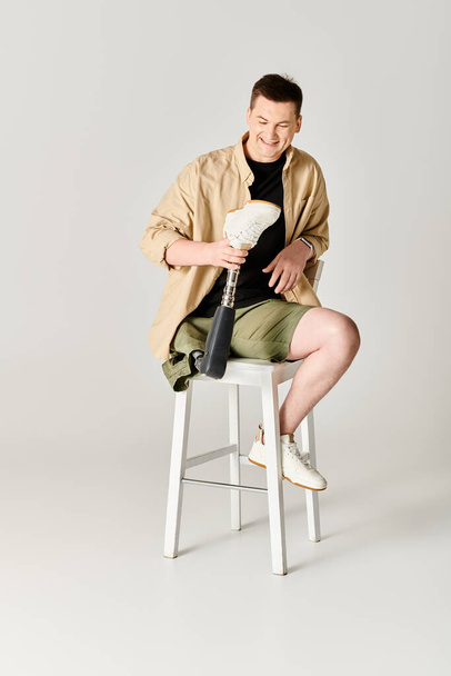 Красивый мужчина в повседневной одежде с протезной ногой, сидящий на стуле. - Фото, изображение