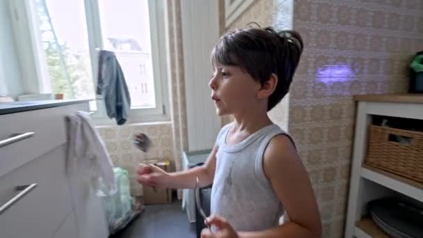 Maluch koryguje błąd - Mały chłopiec powraca zapasową łyżkę z powrotem w szafie kuchennej - Materiał filmowy, wideo