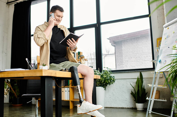 Un bel homme d'affaires avec une prothèse de jambe est assis à une table, parlant sur un téléphone portable. - Photo, image