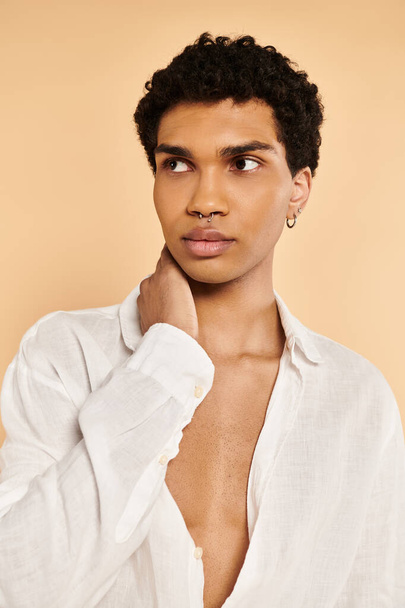 kuszące szykowny Afryki amerykański człowiek w eleganckim białym ubraniu patrząc daleko na beżowym tle - Zdjęcie, obraz
