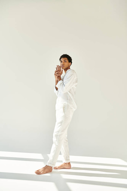 guapo joven afroamericano hombre en traje blanco y mirando a la cámara en el fondo beige - Foto, Imagen