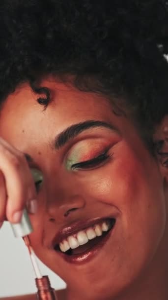 Függőleges portré egy fiatal modell sivár afro haj és fényes smink. Rúzsos kockákat fest. Lassú mozgás, közelkép. Stúdió felvétel. - Felvétel, videó