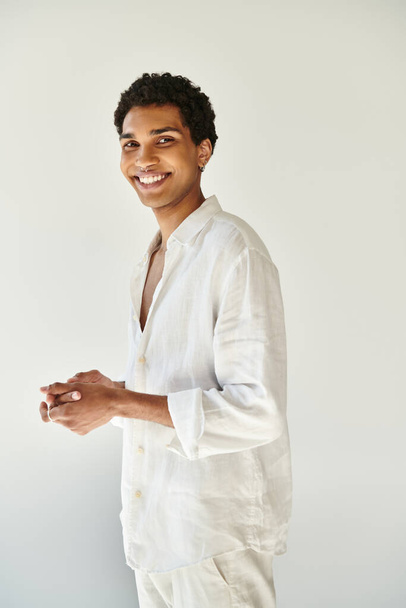 positivo sofisticato afroamericano uomo in lino abbigliamento sorridente alla fotocamera su sfondo beige - Foto, immagini