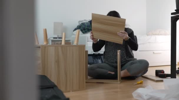 Experiencia en ensamblaje de muebles capturada - Mujer animada construyendo mesita de noche, enfatizando las técnicas de bricolaje en la decoración del hogar, reflejando la emoción de reubicar y personalizar un nuevo espacio - Imágenes, Vídeo