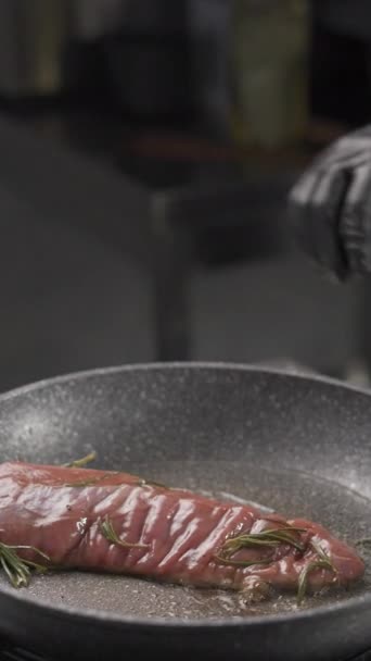 Ένα κομμάτι βοδινό φιλέτο τηγανίζεται στο τηγάνι. Σεφ flips νόστιμο ψητό κρέας στην κουζίνα. Κάθετη προβολή - Πλάνα, βίντεο