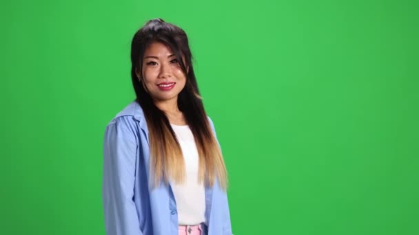 Kendine güvenen genç Asyalı bayan, günlük kıyafetli öğrenci canlı yeşil stüdyo geçmişiyle kameraya bakıyor. Uzayı kopyala İnsan duyguları kavramı, kendini ifade etme, moda, tarz. Ad - Video, Çekim