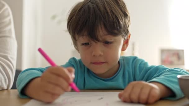 Petit garçon regarde sa mère pour approbation pendant les devoirs - Séquence, vidéo