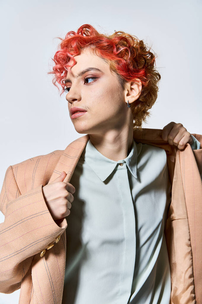 Μια εντυπωσιακή γυναίκα με κόκκινα μαλλιά σε ένα μοντέρνο σακάκι. - Φωτογραφία, εικόνα