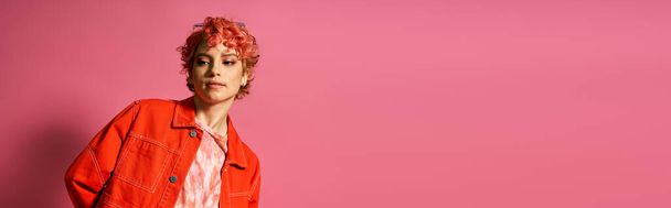 Egy vörös hajú nő áll a rózsaszín fal előtt.. - Fotó, kép