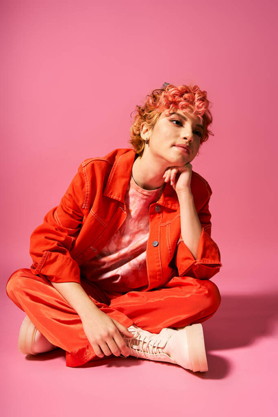 Una donna glamour medita mentre siede su uno sfondo rosa vibrante. - Foto, immagini