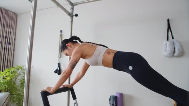 Lange shot van jonge sportvrouw training op fitness apparaat binnen - Video